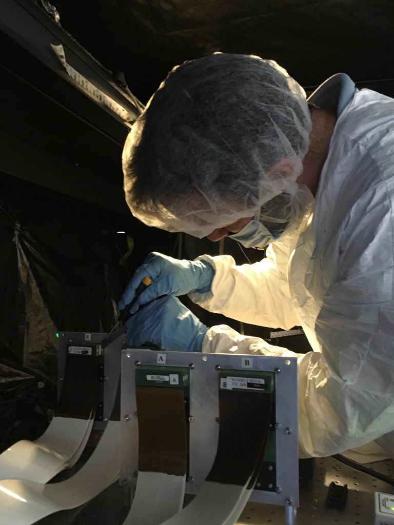 Dr. Jared Males leaning over some cable assemblies to disconnect them.