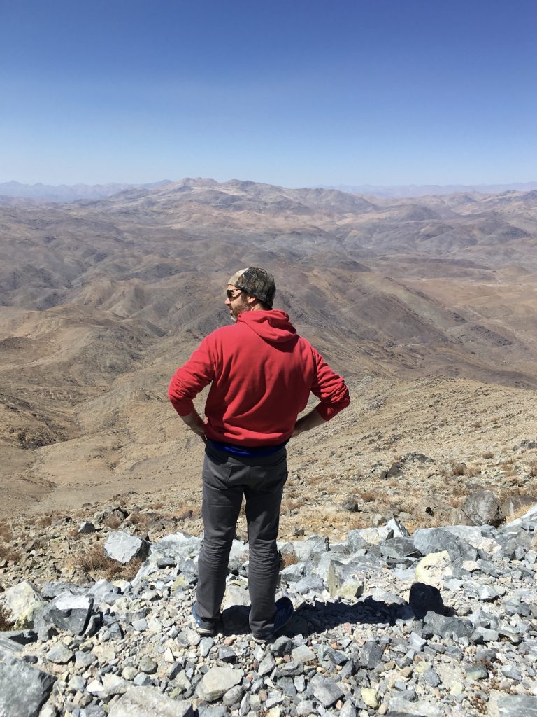 Dr. Jared Males stands on the mountain, overlooking the valley below.