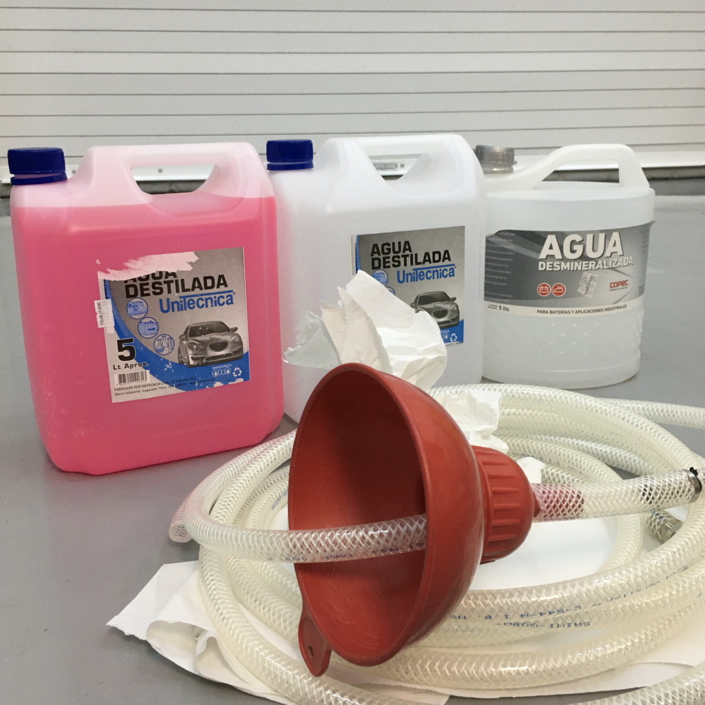 Containers of pink glycol solution, tubing, and a funnel on the floor of the LCO cleanroom.