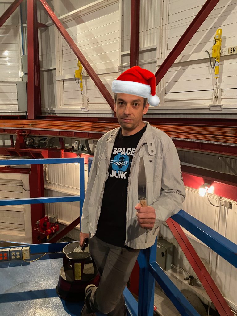 Olivier Guyon standing on the telescope platform with a knife in hand (and a photoshopped Santa Claus hat on his head).
